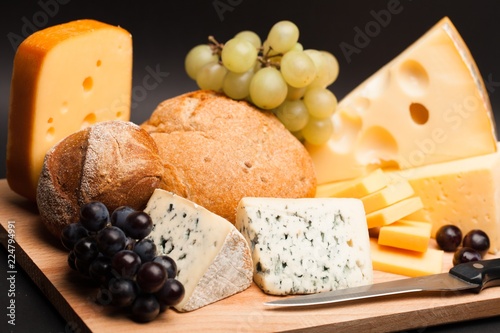 Knife, Cheese, Rolls and Grape on the Wooden Platter on Black