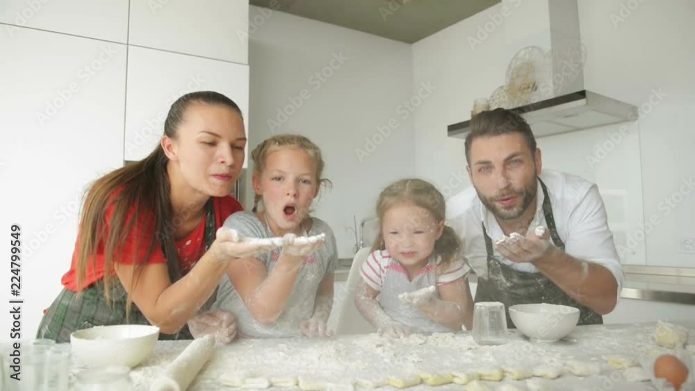 Happy Family With Aprons Are Blowing Flour. They Have a Lot of Fun Together. Good Mood, Slow Motion. Happy Family With Aprons Are Blowing Flour. They Have a Lot of Fun Together. Good Mood, Slow Motion.