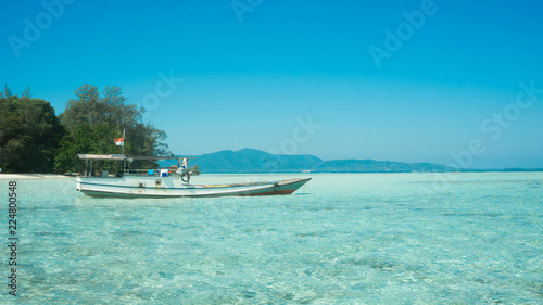 Fototapeta Naklejka Na Ścianę i Meble -  traditional boat transportation on the shallow sea with transparent clear and island in distance