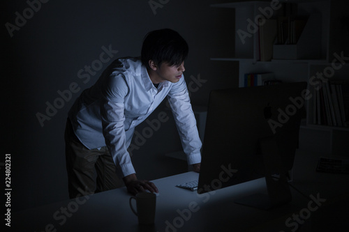 深夜のオフィスでPC画面を凝視しているプロジェクトマネージャー