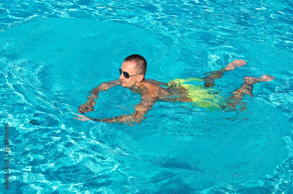 Young man enjoys swimming in outdoor pool