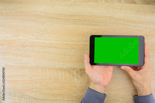 Businessman holding digital tablet with green screen.