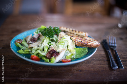 Fresh caesar salad in the plate on dark wooden table.