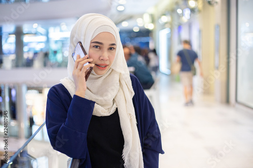 young muslim woman using phone in supermarket.