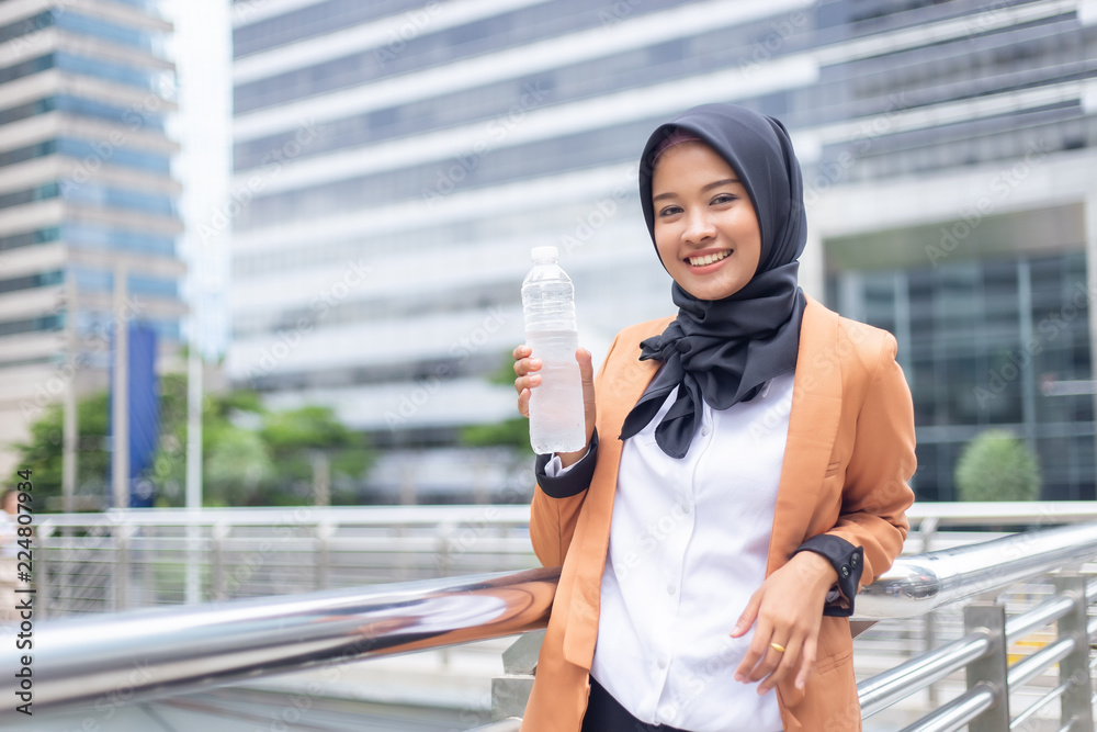 Fototapeta premium Beautiful young asian muslim with bottled water.