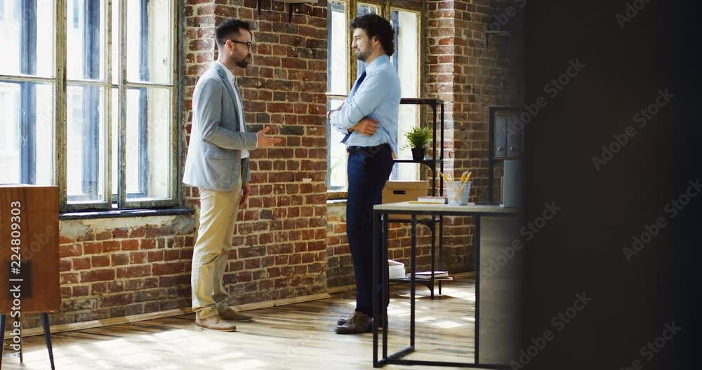 Male Caucasian emloyee coming to the office of his boss and having a conversation about new business project. Male Caucasian emloyee coming to the office of his boss and having a conversation about new business project.