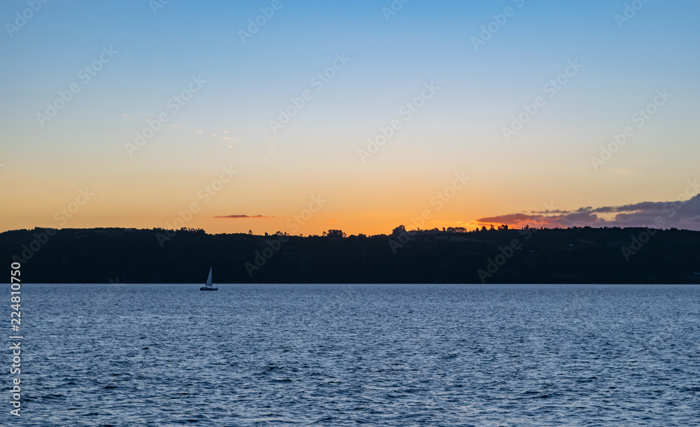 small sailboat sailing at sunset
