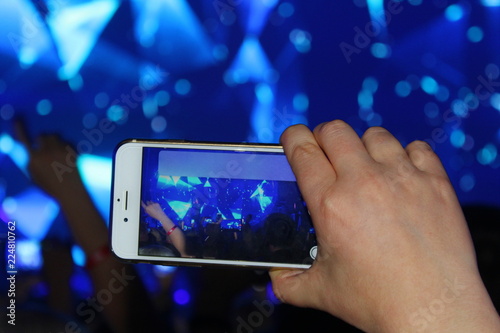 at the concert the hand holds the phone and take the scene