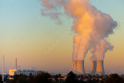 cooling towers with water steam in morning light, nuclear plant