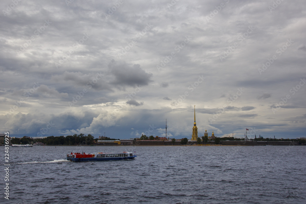 view from the Neva river with boats passing by to the Peter and Paul fortress, with a beautiful cloudy sky