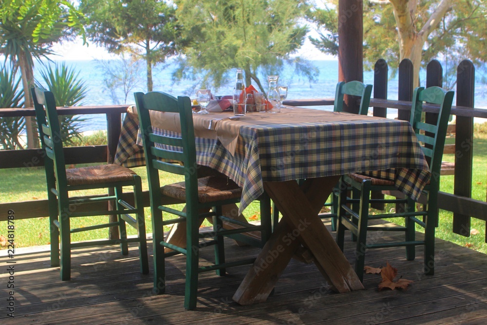 Due to economic crisis, tourists paid the low bill and left behind an almost empty table at a traditional greek taverna - restaurant by the sea at summer in high season
