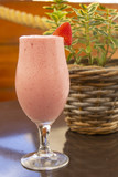 delicious strawberry milkshake with strawberry berry on top of the glass, with a tube on the table in the cafe, a good drink in the hot summer and a treat for children