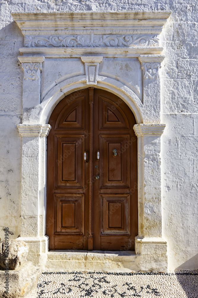 an old white portal with columns and a large wooden door