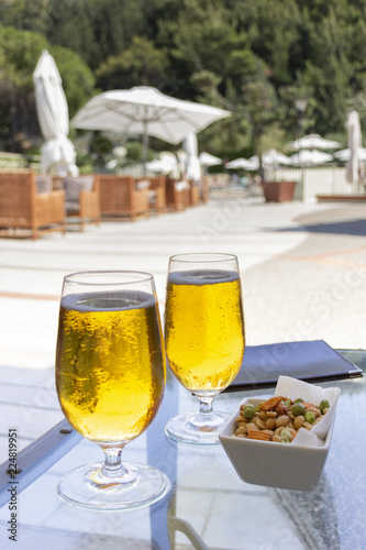 a glass of cold beer with bubbles, different nuts, hot summer day on an outdoor terrace in a bar by the sea