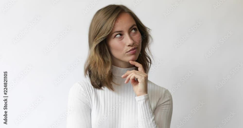Young brunette woman on white background considering and smiles while looking around Young brunette woman on white background considering and smiles while looking around