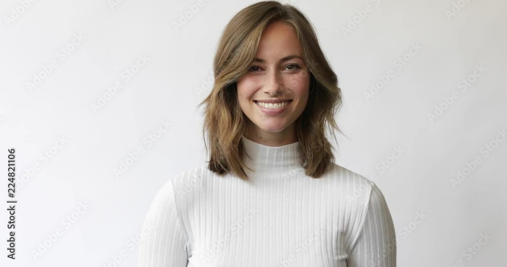 Young brunette woman on white background smiles and laughs to the camera and touch the hair
