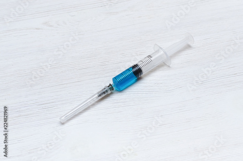 Syringe with blue liquid medicine drug on the doctor table.