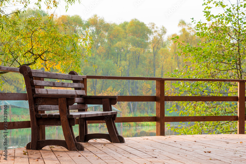 Wooden bench on a bridge over a lake in an autumn park