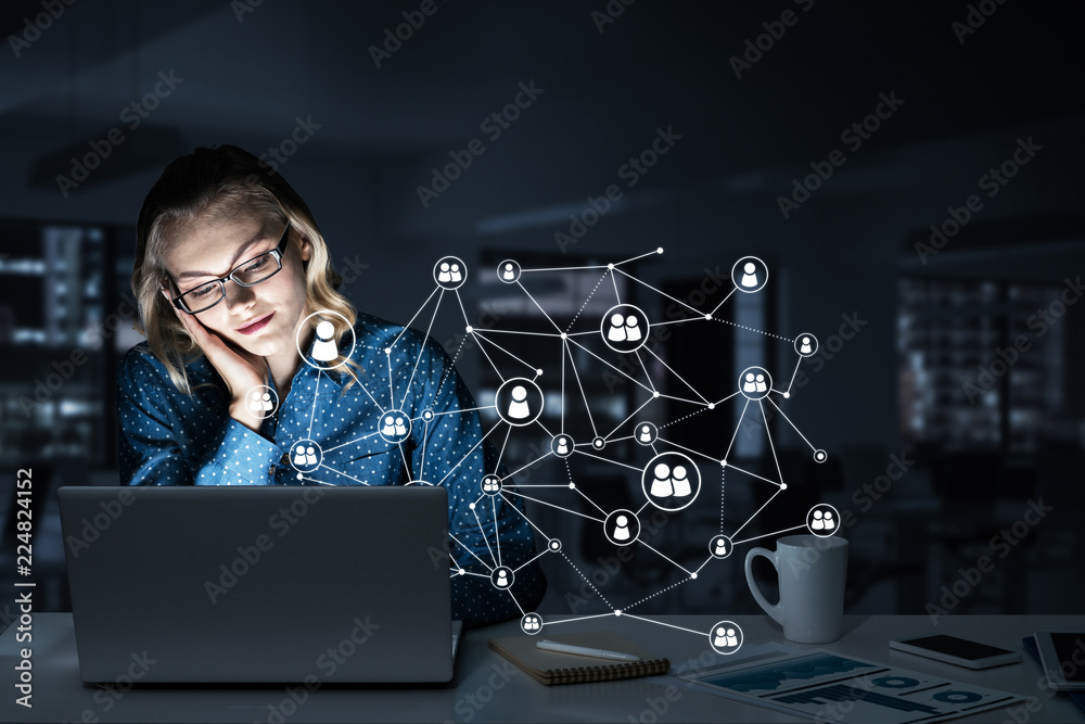 Attractive blonde wearing glasses in dark office using laptop. M Attractive blonde wearing glasses in dark office using laptop. M