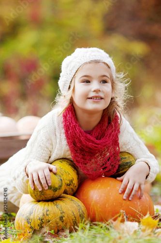 Fotografia Cute little girl playing with pumpkins in autumn park