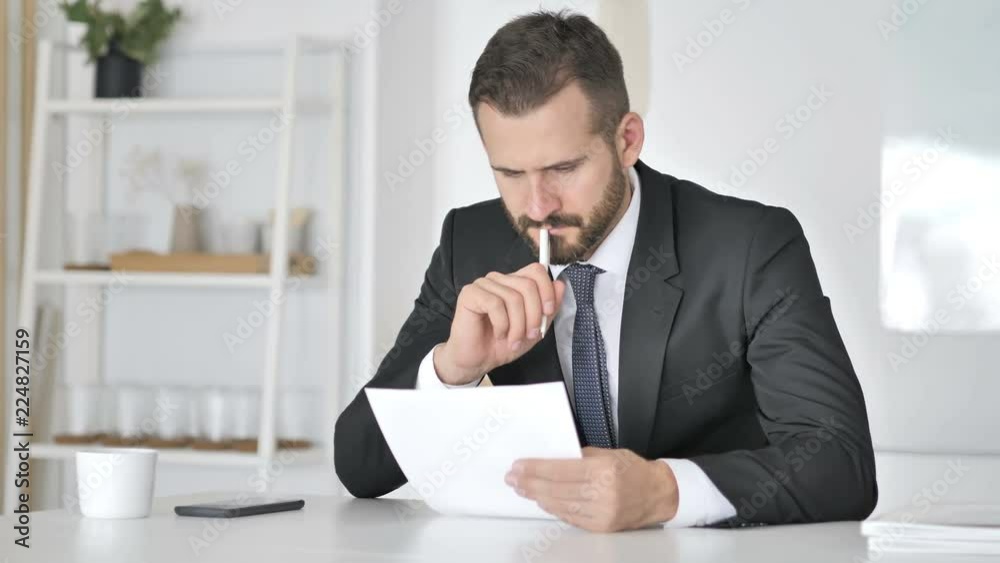 Pensive Businessman Reading Documents in Office, Paperwork Pensive Businessman Reading Documents in Office, Paperwork
