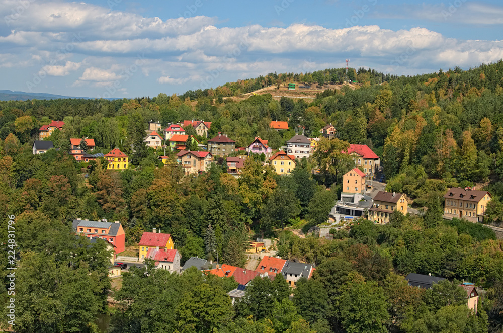 Picturesque landscape photo of Loket town. Colored residential houses on the slope of the mountain with ancient trees by summer sunny day. Bohemia, Sokolov, Karlovarsky Region, Czech Republic - obrazy, fototapety, plakaty 