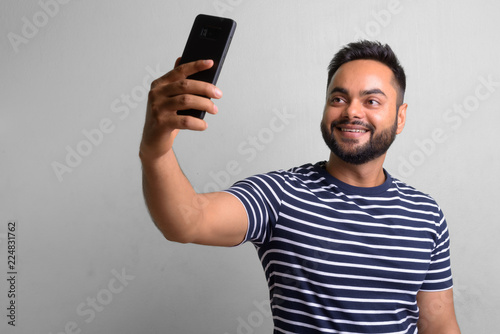 Young bearded Indian man against white background © Ranta Images