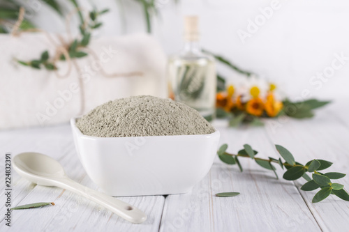 Preparing cosmetic mud mask with various skincare products. Dry clay powder in bowl. Natural cosmetics for home or salon spa treatment. On white background.