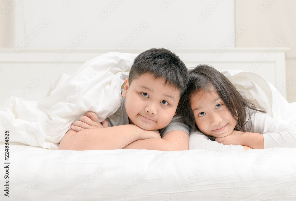 Two happy sibling children lying under blanket Two happy sibling children lying under blanket