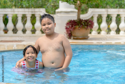 Happy brother and sister play in swimming pool,
