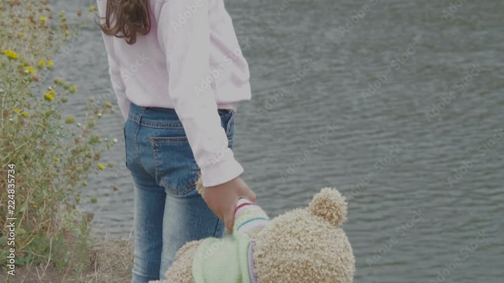 A child with a bear in nature. Happy little girl hugging a teddy bear.