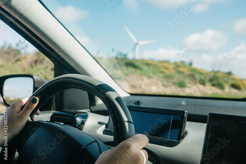 Close-up. The driver's hand on the steering wheel. The driver or traveler or tourist is driving a car. Everyday riding or traveling.