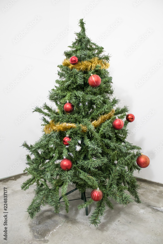 Detailed green christmas tree with red decorations in a white background