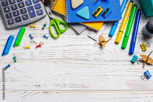 On a white table in a chaotic order lie: calculator, elastic, paper clips. Back to school background.