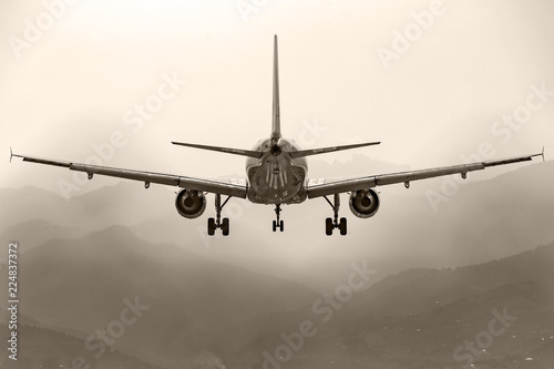 Aircraft, airliner with landing gear comes to land on the background of the mountains. Rear view.