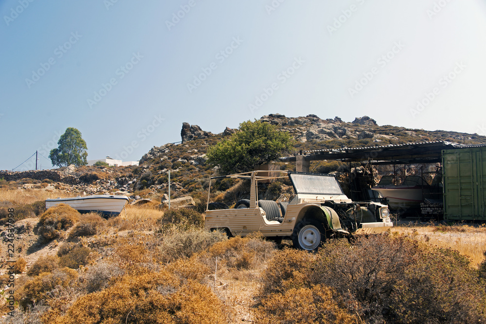 Obraz premium A view of a wrecked car and a baot in the land of Patmos, Greece in summer