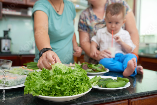 Woman taking fresh green lettuce when cooking salad for her family
