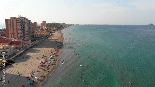 Panoramic sunset view to long sandy beach of La Manga del Mar Menor. Aerial view to people swimming and relaxing on the beach. La Manga del Mar Menor, Cartagena, Murcia, Spain, Summer 2018.