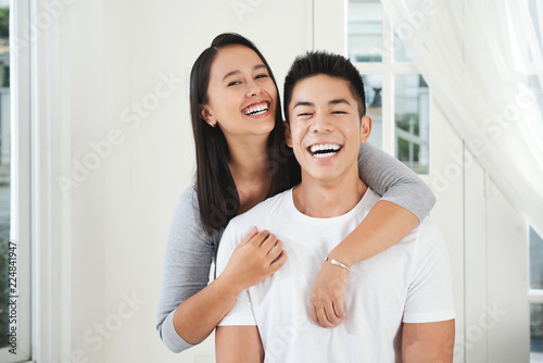 Portrait of young laughing couple hugging and looking at camera