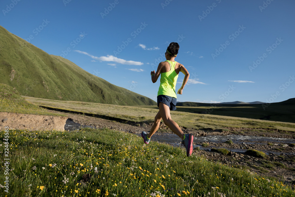 Young fitness woman trail runner running on grassland Young fitness woman trail runner running on grassland