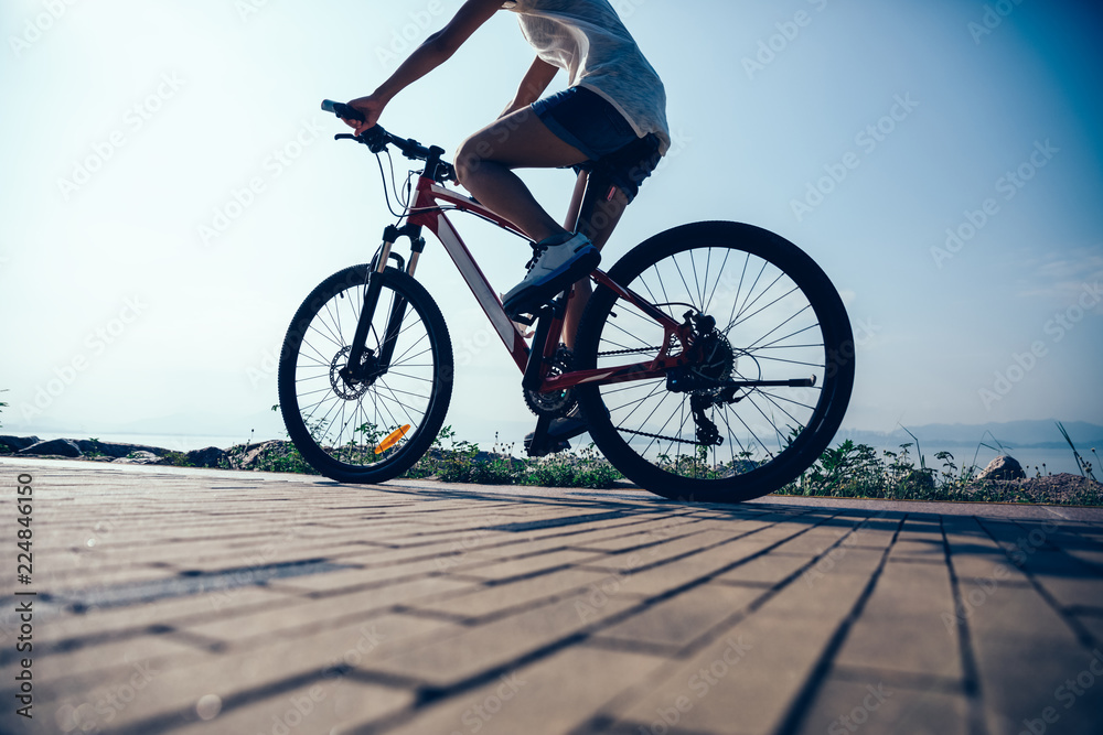 Cycling woman riding mountain mike on sunrise seaside Cycling woman riding mountain mike on sunrise seaside