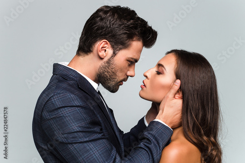 Give me a kiss. Portrait of young beautiful couple looking at their eyes while standing against white background photo