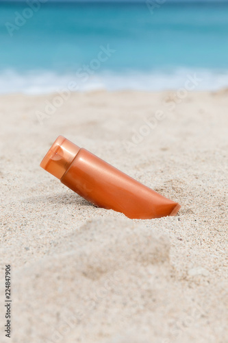 Sunscreen sunblock spf cream on the sea beach sand summer tropical holiday concept