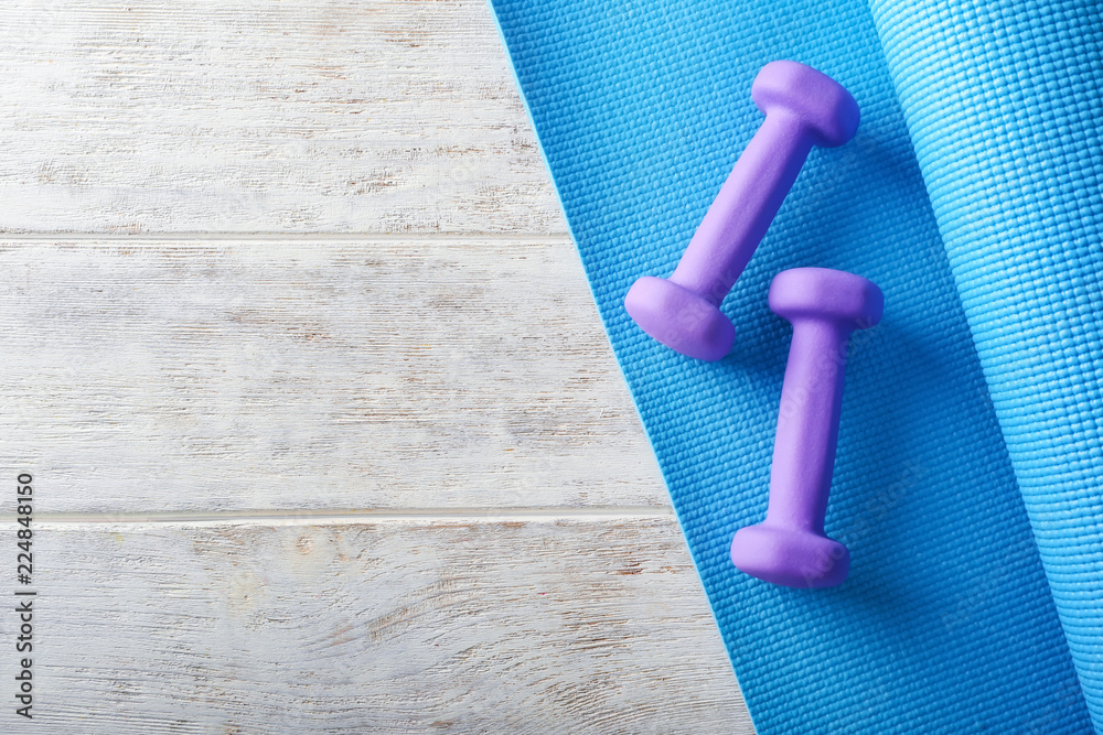 Yoga mat with dumbbells on light wooden background Stock Photo Adobe Stock