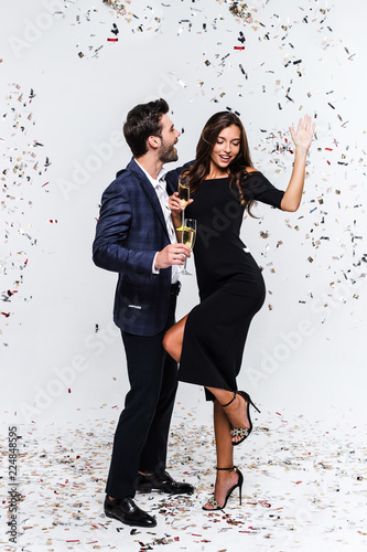Little party newer killed nobody. Full length of young beautiful couple bonding and dancing while standing against white background with confetti 