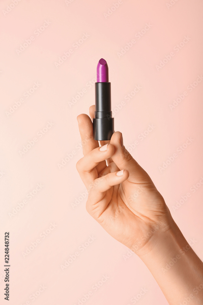 Woman holding bright lipstick on color background Woman holding bright lipstick on color background