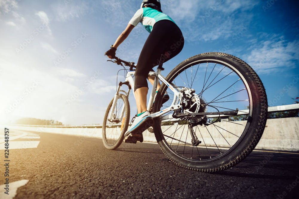Fototapeta premium Woman cyclist riding Mountain Bike on highway