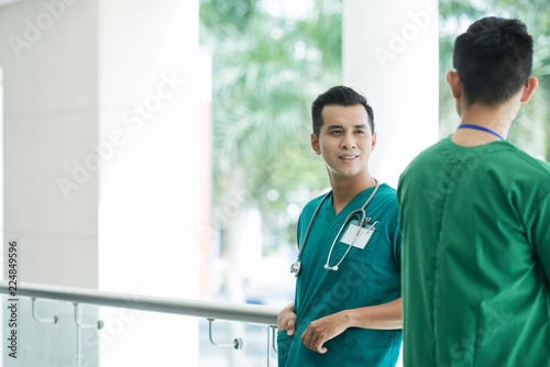 Smiling Asian medical worker talking to colleague