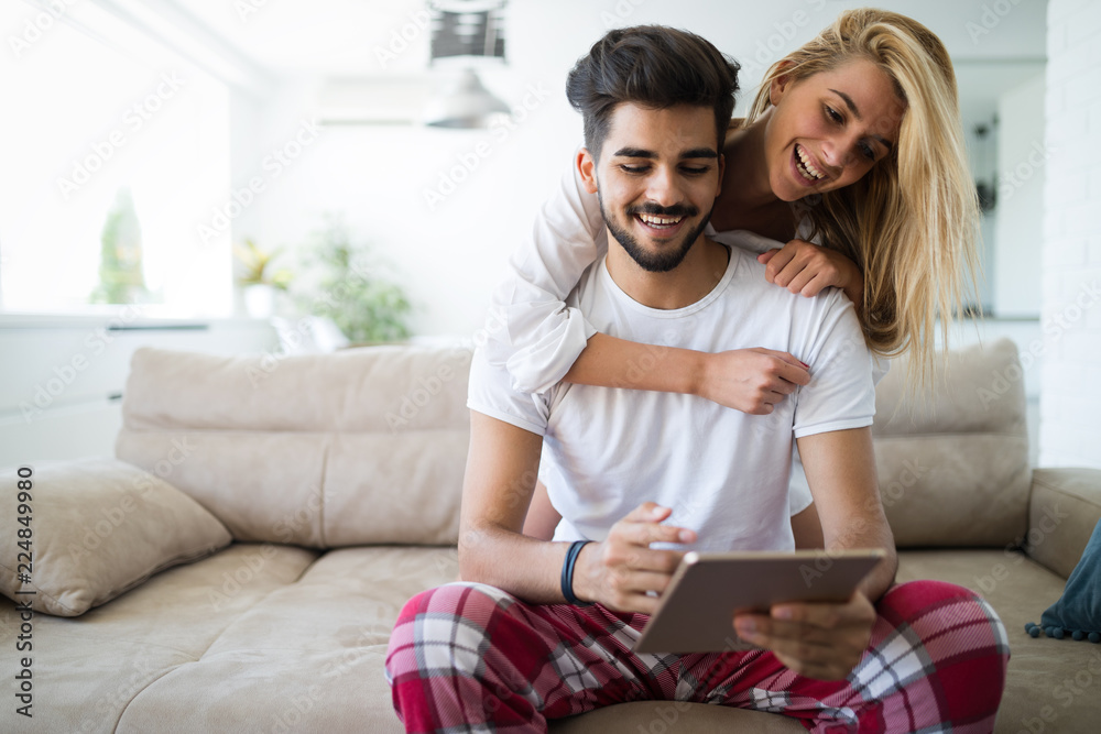 Happy couple in love using tablet in pajamas