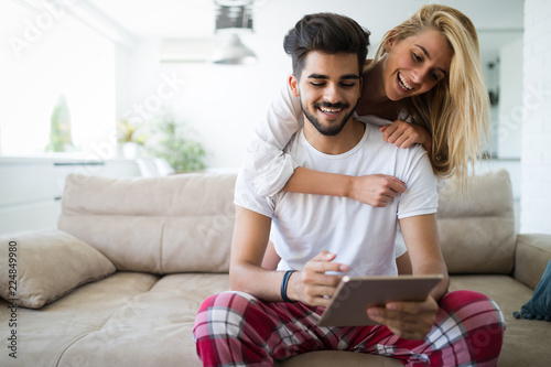 Happy couple in love using tablet in pajamas